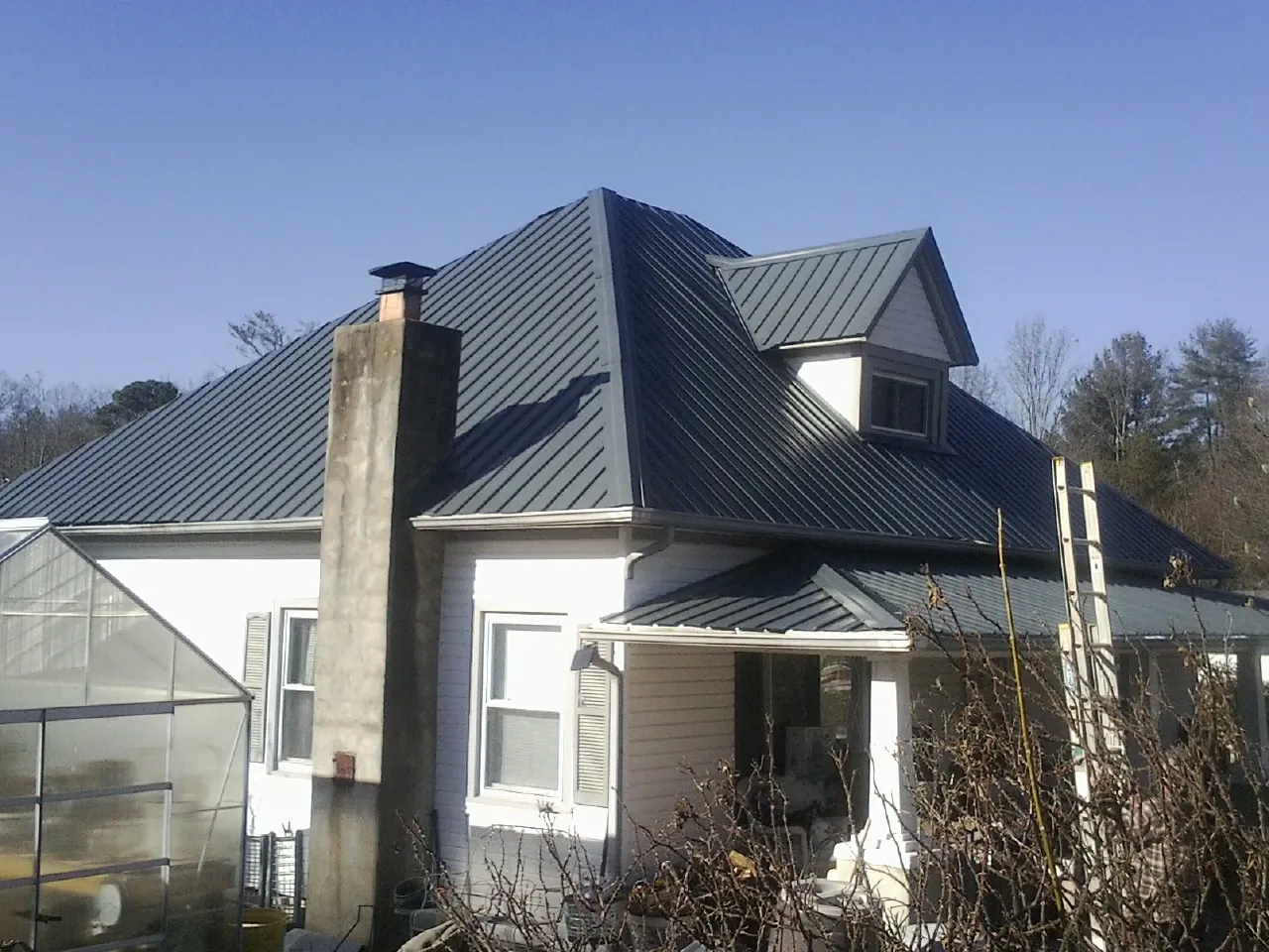 Dark blue standing seam metal roof on a white farmhouse with dormer — Slate & Tile Roof Repair by Roofing Brothers in Canistota