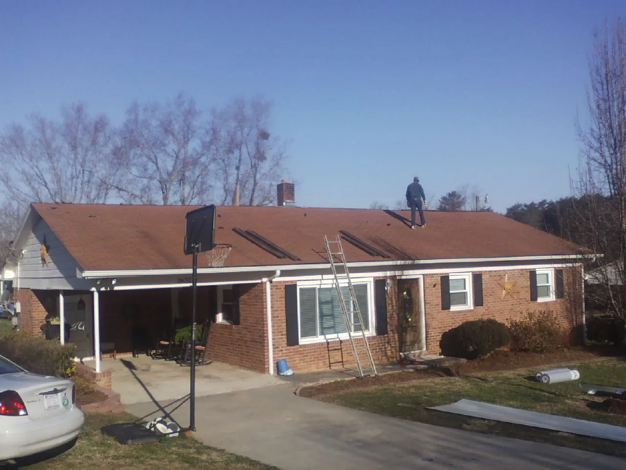 Roofer stripping a shingle roof on a brick ranch before metal panels in Canistota
