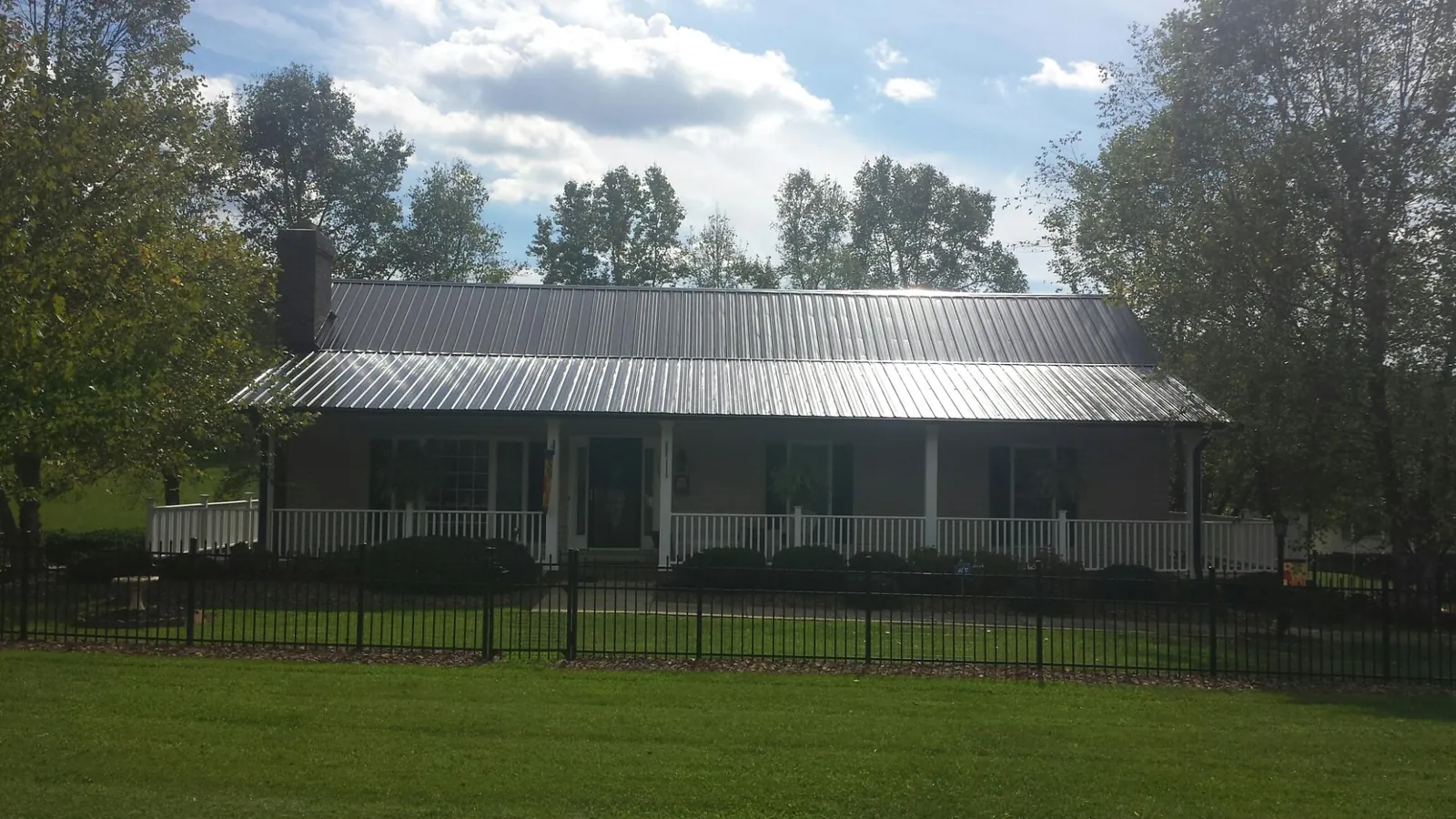 Gray metal roof on a brick ranch with a full width front porch — Gutter Guard Installation work by our crew in Canistota