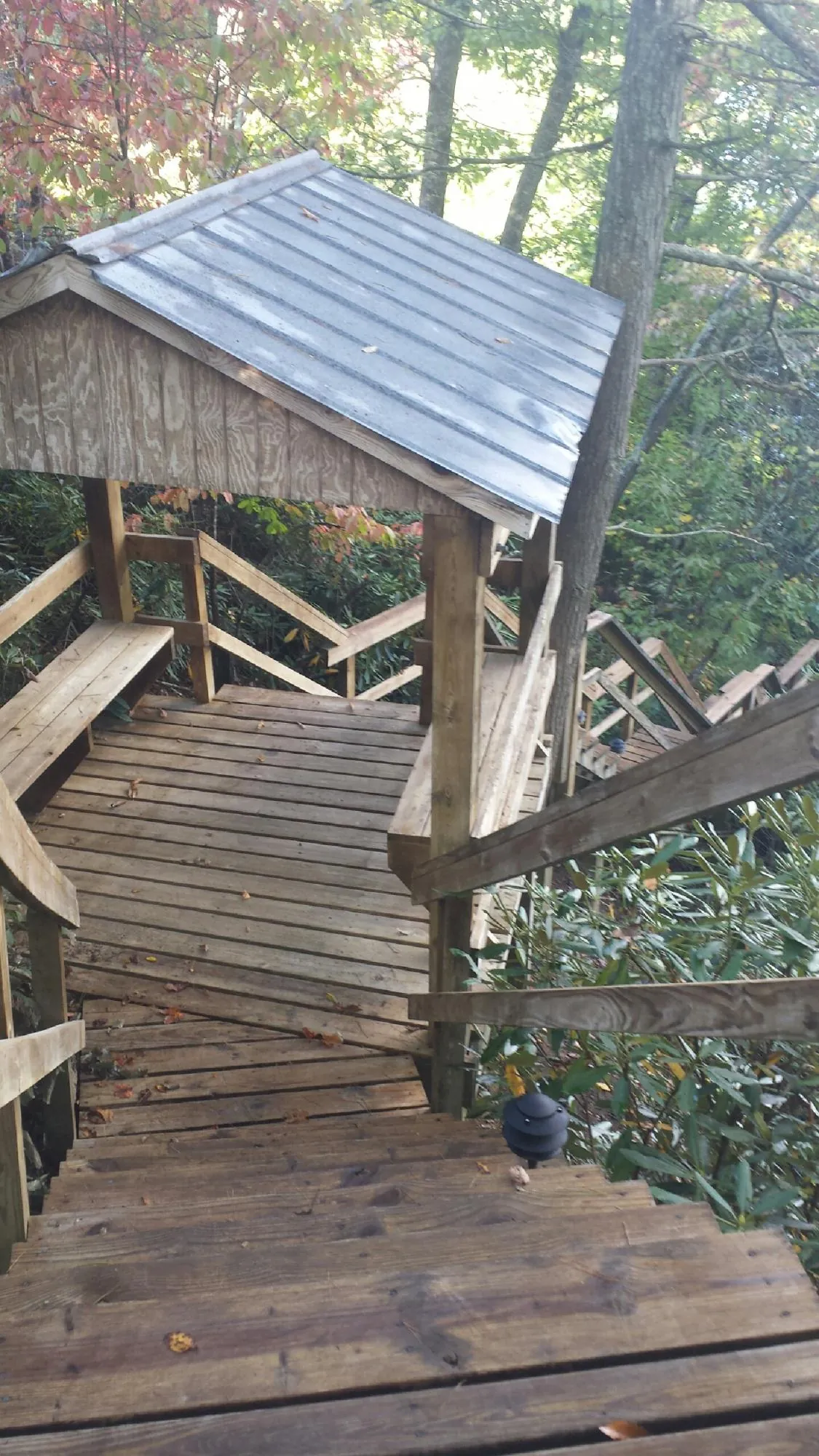 Metal roofed shelter over wooden steps on a wooded walkway — Skylight Repair & Installation work by our crew in Canistota