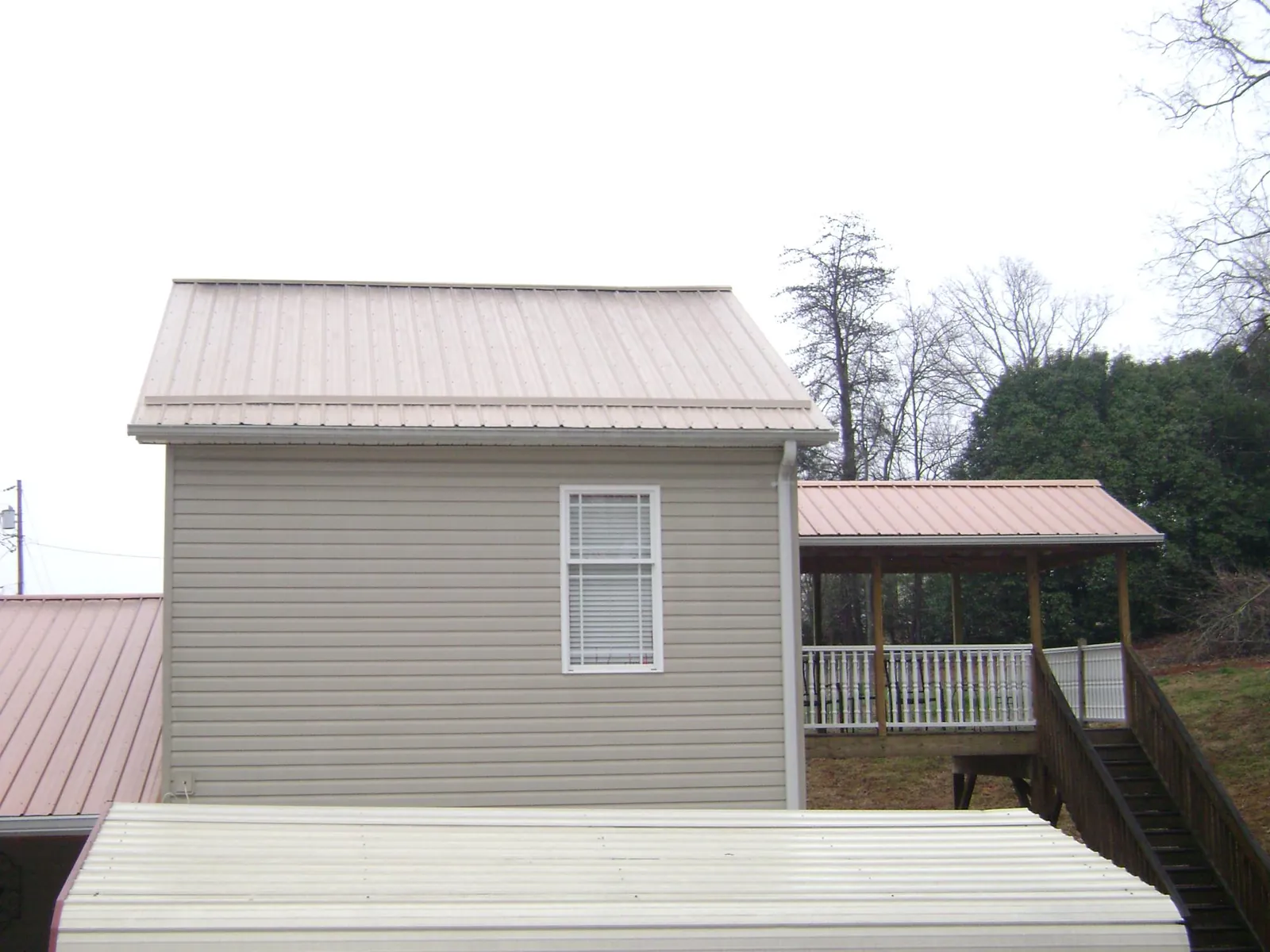 Tan metal roofs on a two story addition and attached porch, from a Roof Replacement job in Canistota