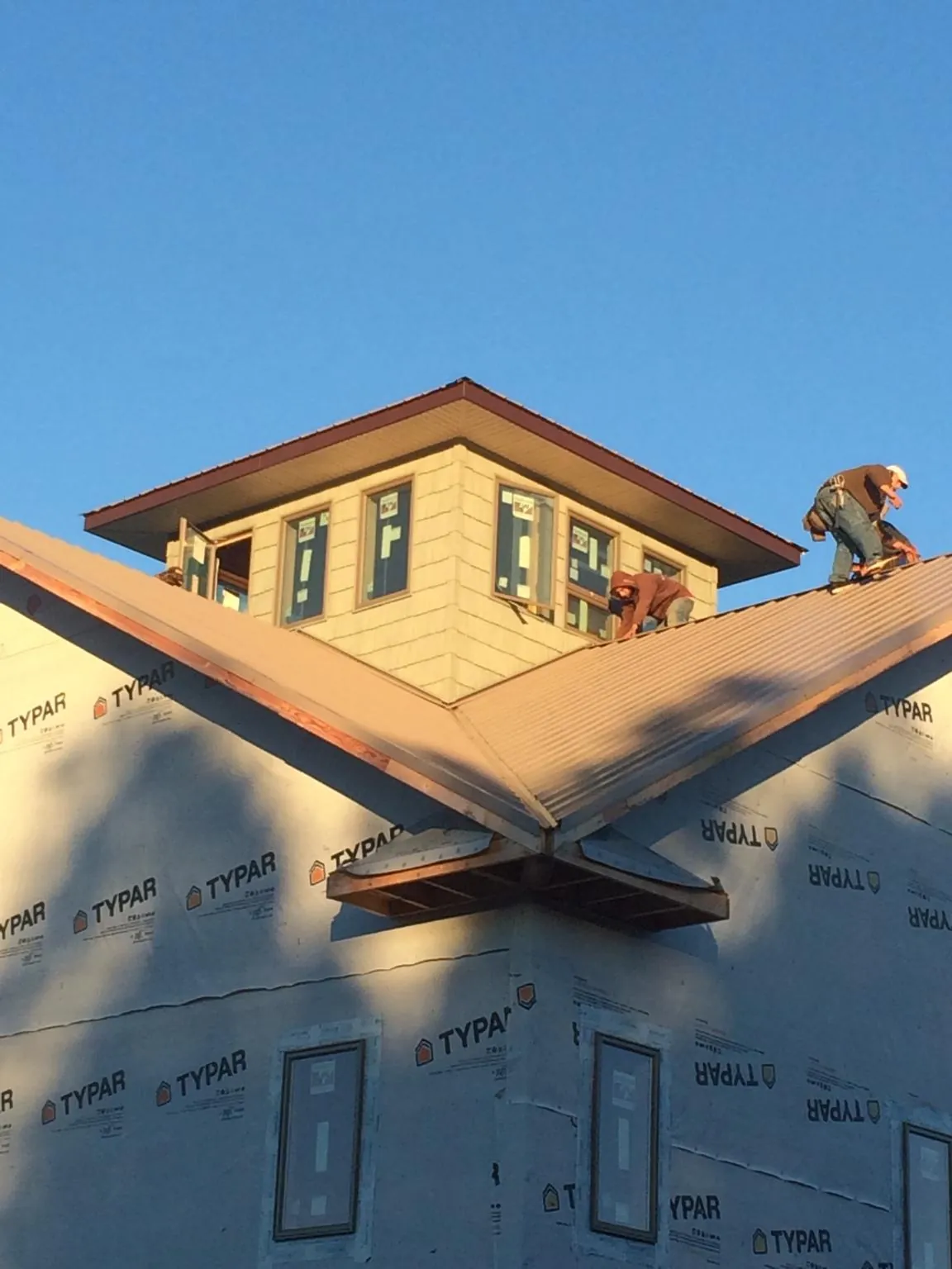 Roofers working around a rooftop cupola on a new metal roof at sunset — Roof Waterproofing in Canistota by Roofing Brothers
